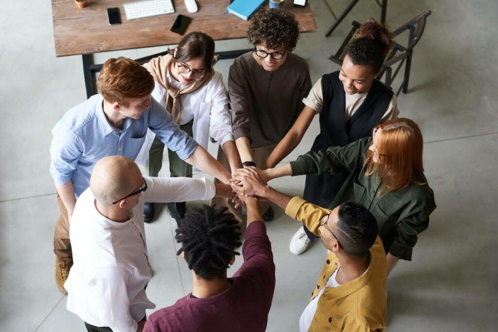 Eight employees happily doing a team work gesture.