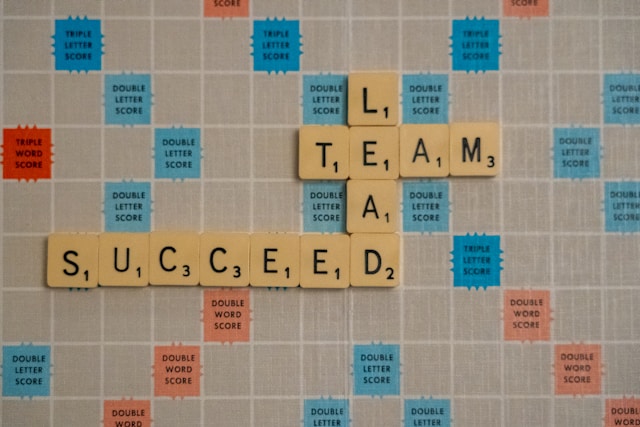 Scrabble tiles spelling out the words lead team and succeed